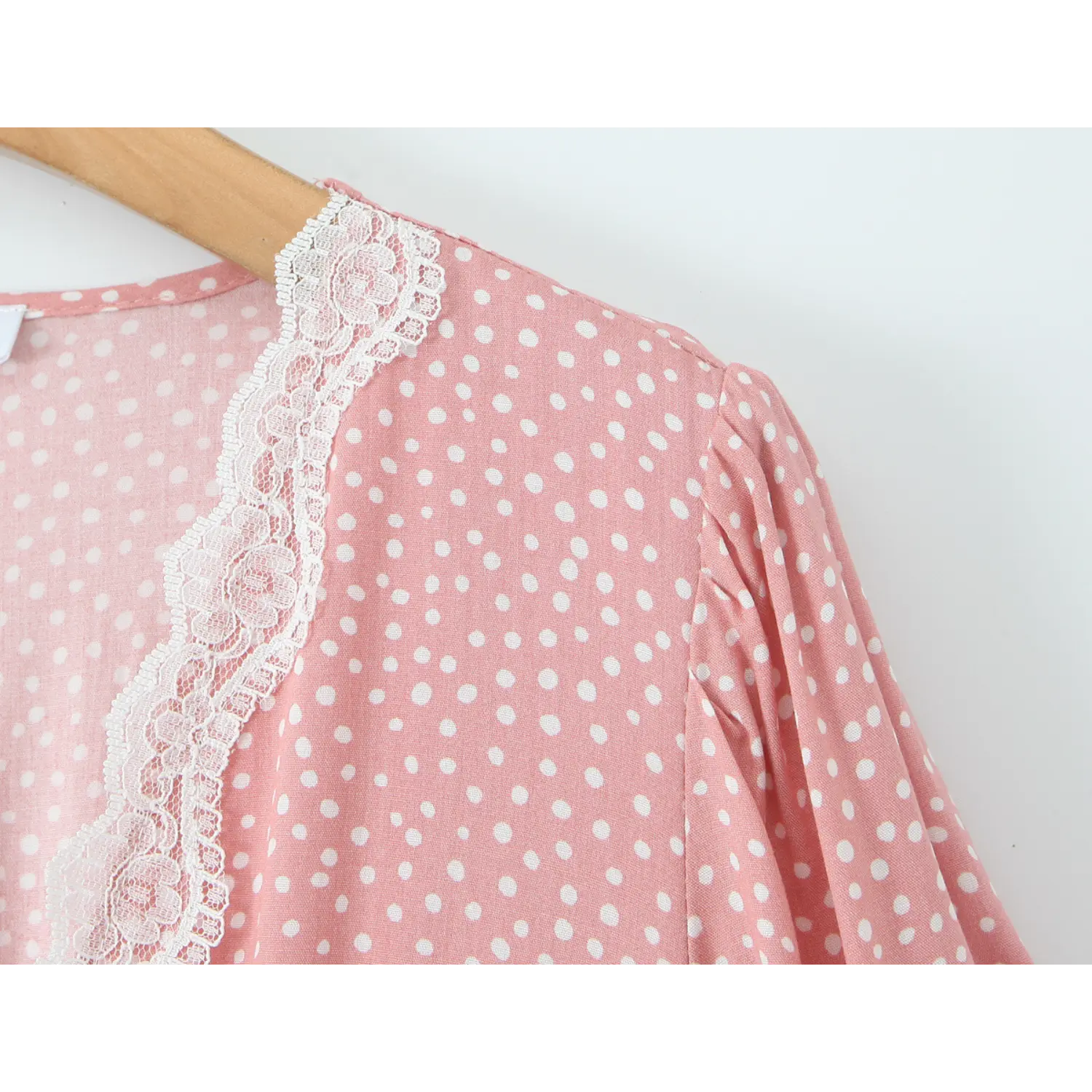 Partial close‑up of shoulder lace trim and puff sleeve on wooden hanger