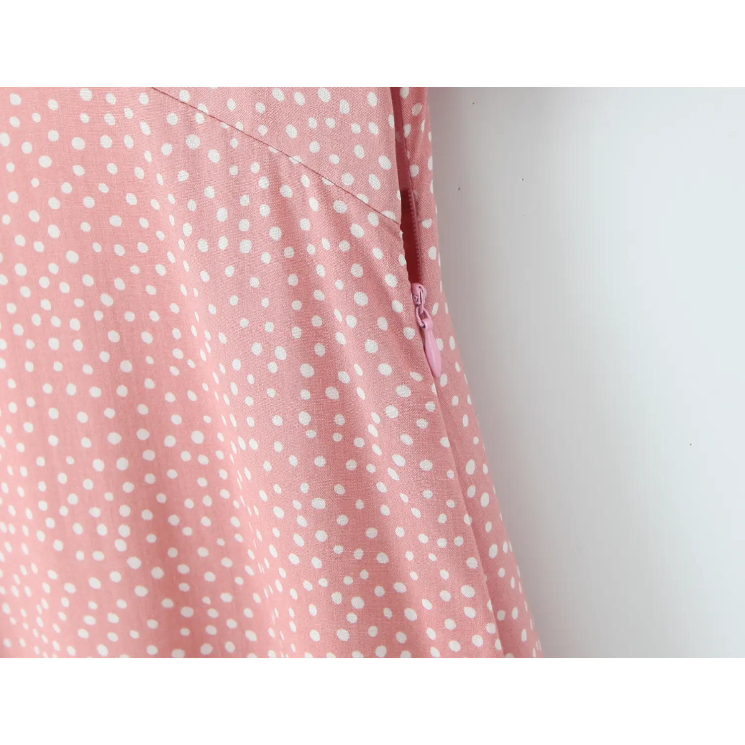 Partial close‑up of concealed side zipper on pink polka dot maxi dress