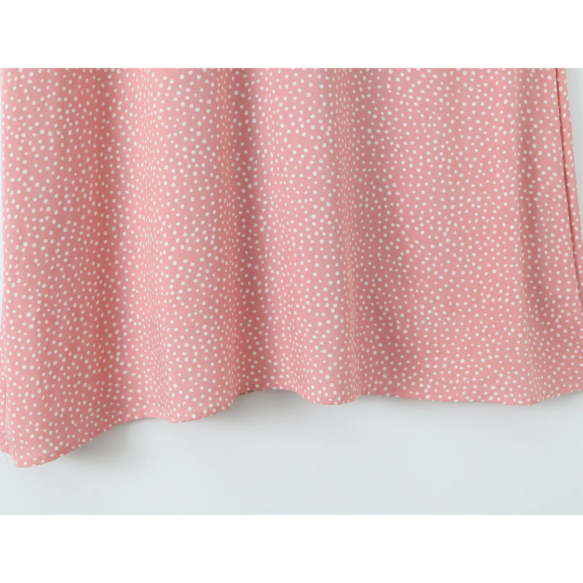 View of flowy skirt hem, pink white polka dot maxi dress