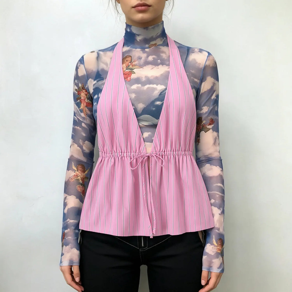 Model wears pink vertical striped halter vest with drawstring tie waist, layered over blue angel cloud print mesh turtleneck