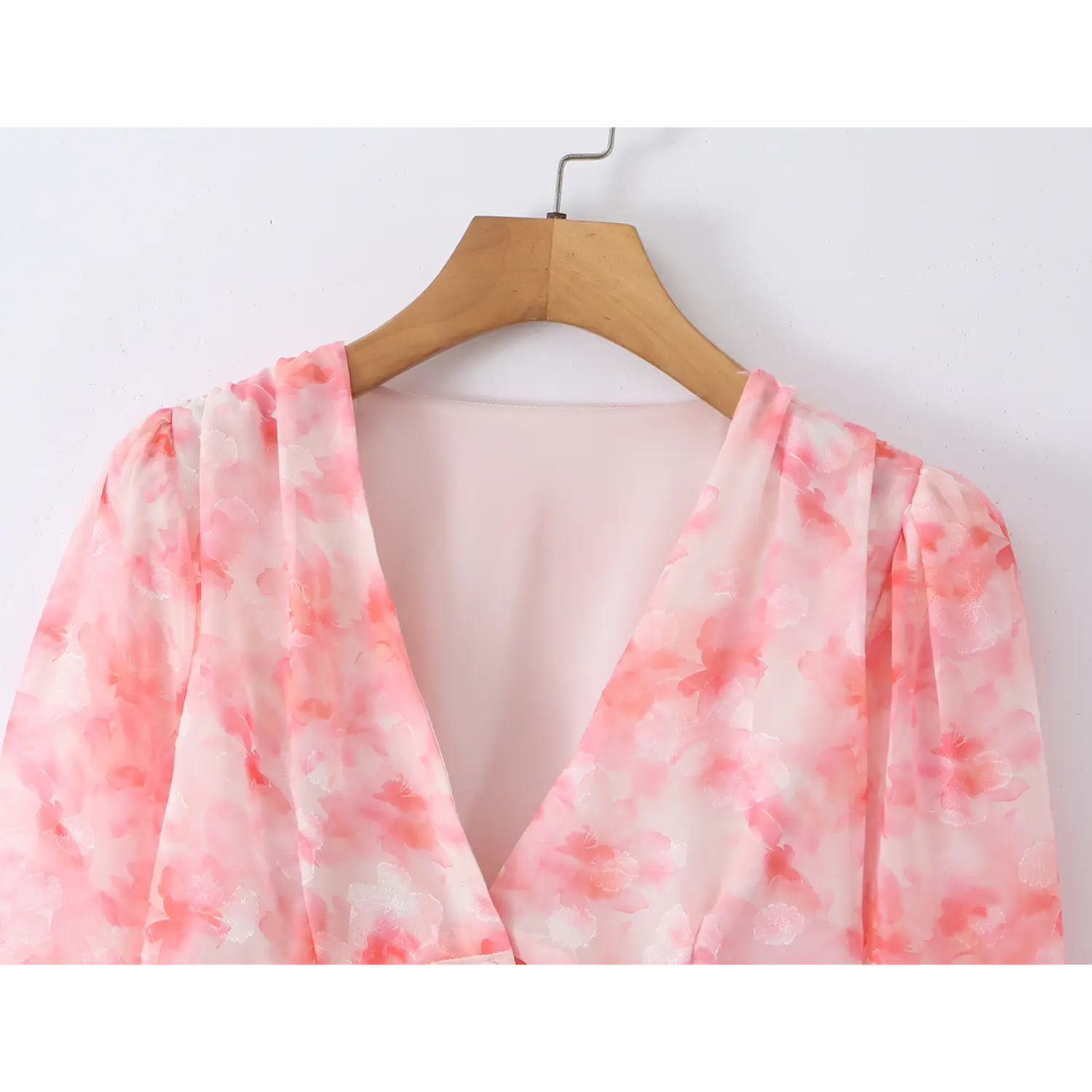 Close‑up of v‑neck and gathered shoulder detail, pink watercolor floral jacquard chiffon fabric, inner lining visible
