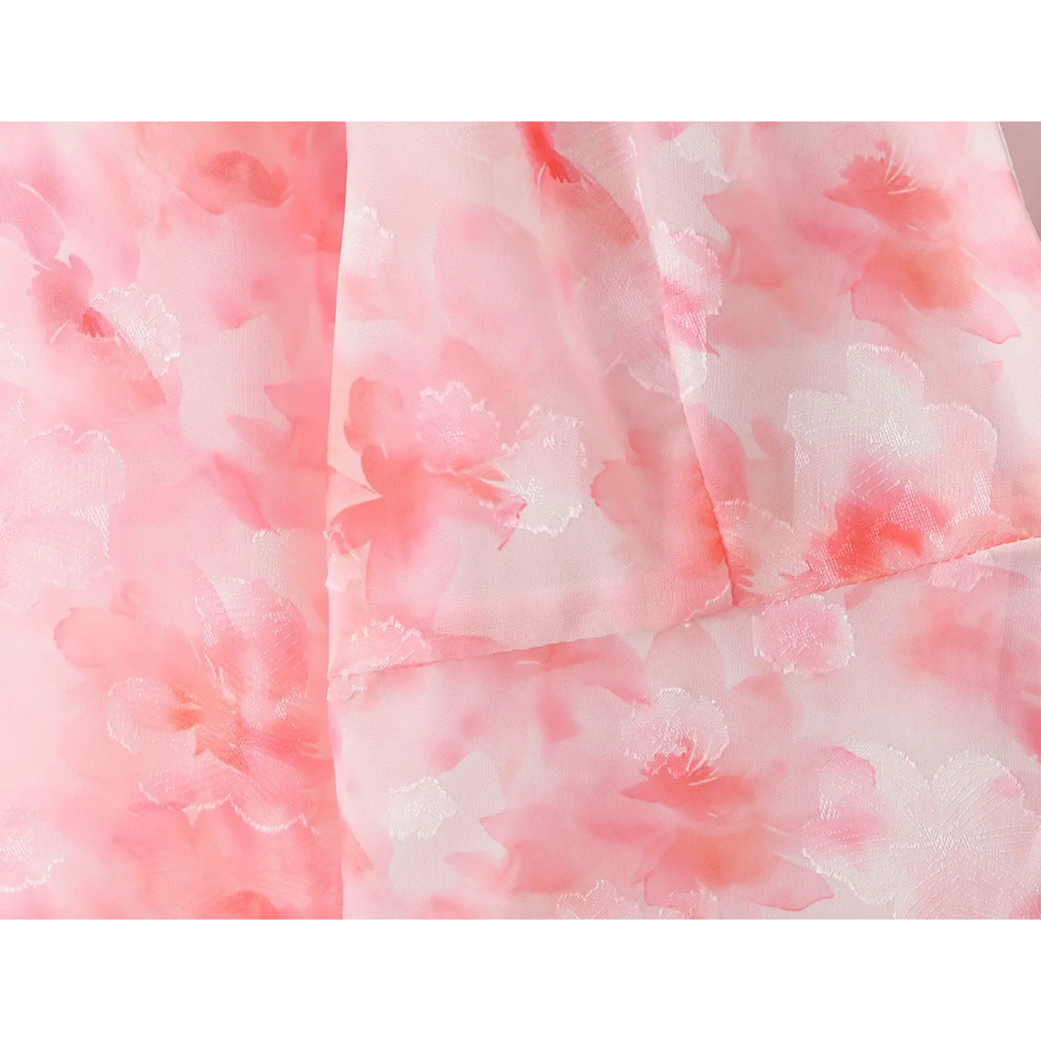 Fabric close‑up, pink watercolor blossom print with subtle jacquard embossed floral texture, sheer chiffon material