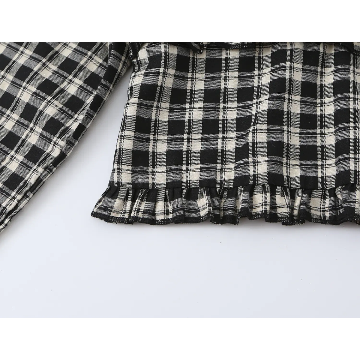 Hem close-up frill ruffle edge of black beige plaid cropped blouse, neat zigzag serged stitching, layered woven check frill hem