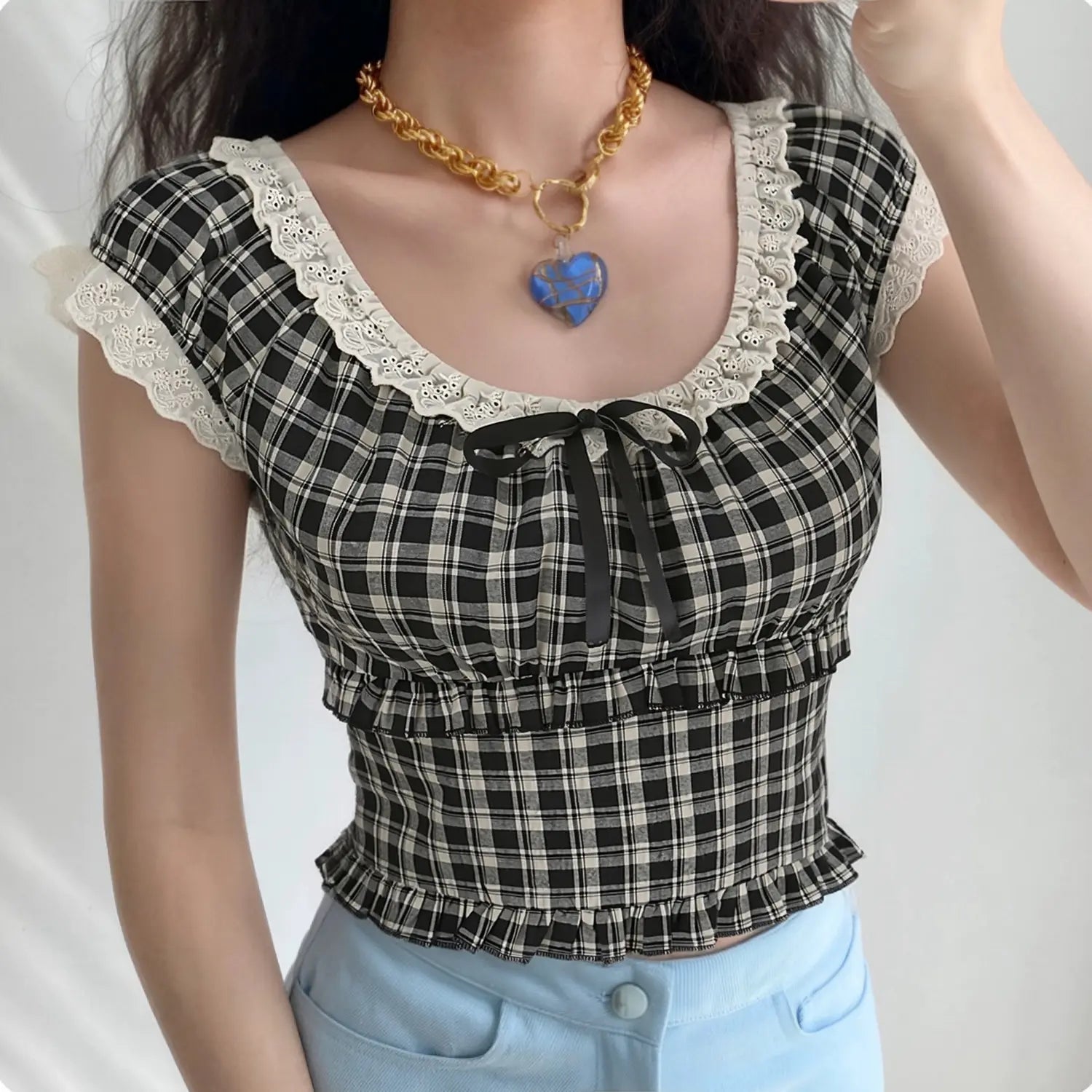 Model wearing vintage y2k black white check cropped blouse, eyelet lace square neck with black satin bow, elastic smocked waist, paired with light blue jeans, sweet casual streetwear outfit