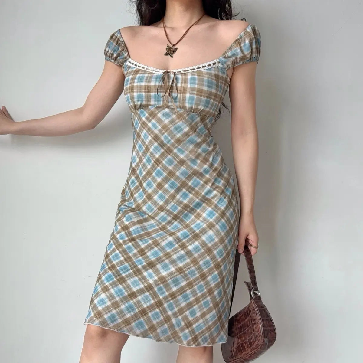 Slight side view of the blue-brown plaid midi dress, showing the fit and puff sleeves.