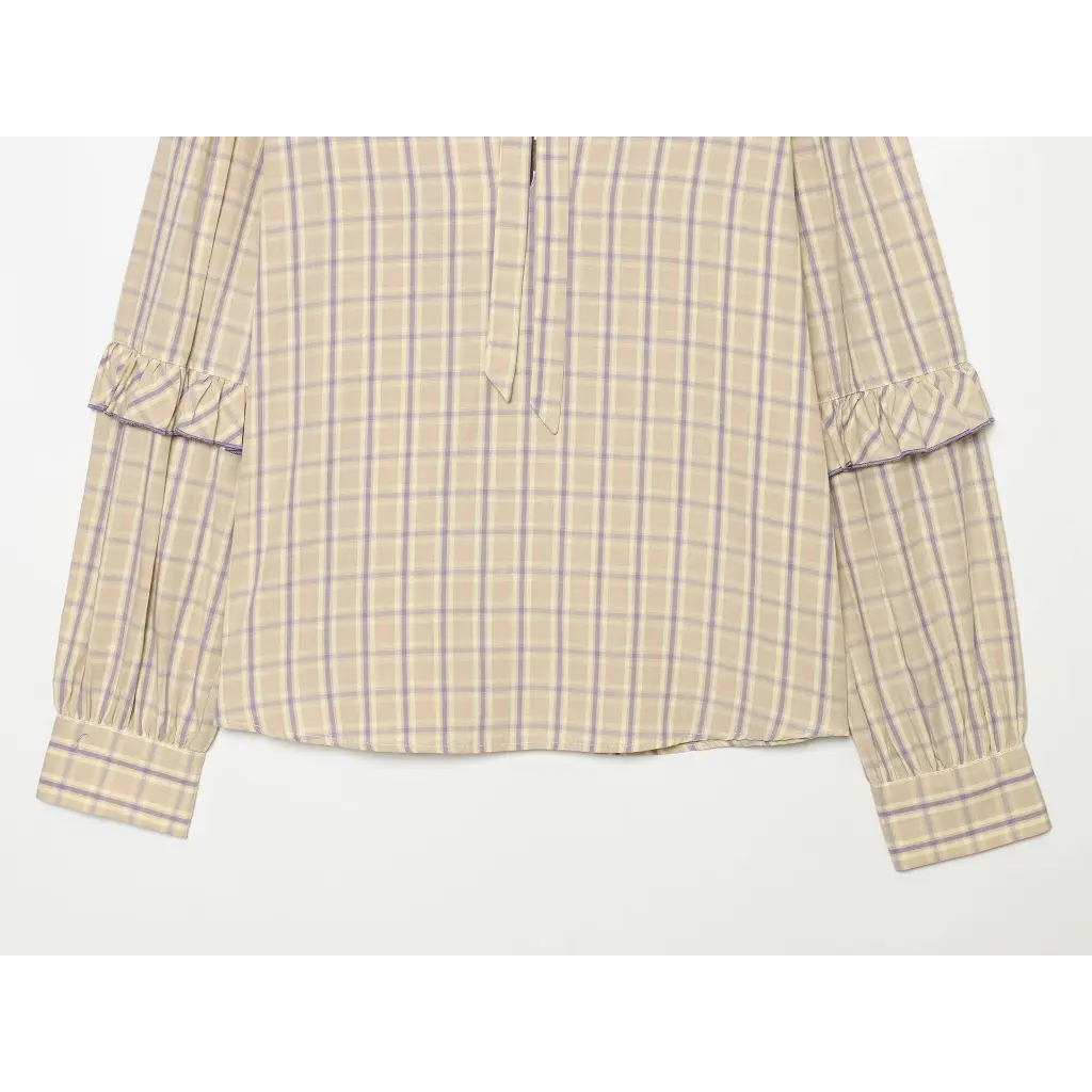 Close-up of blouse hem and gathered cuffs flat lay