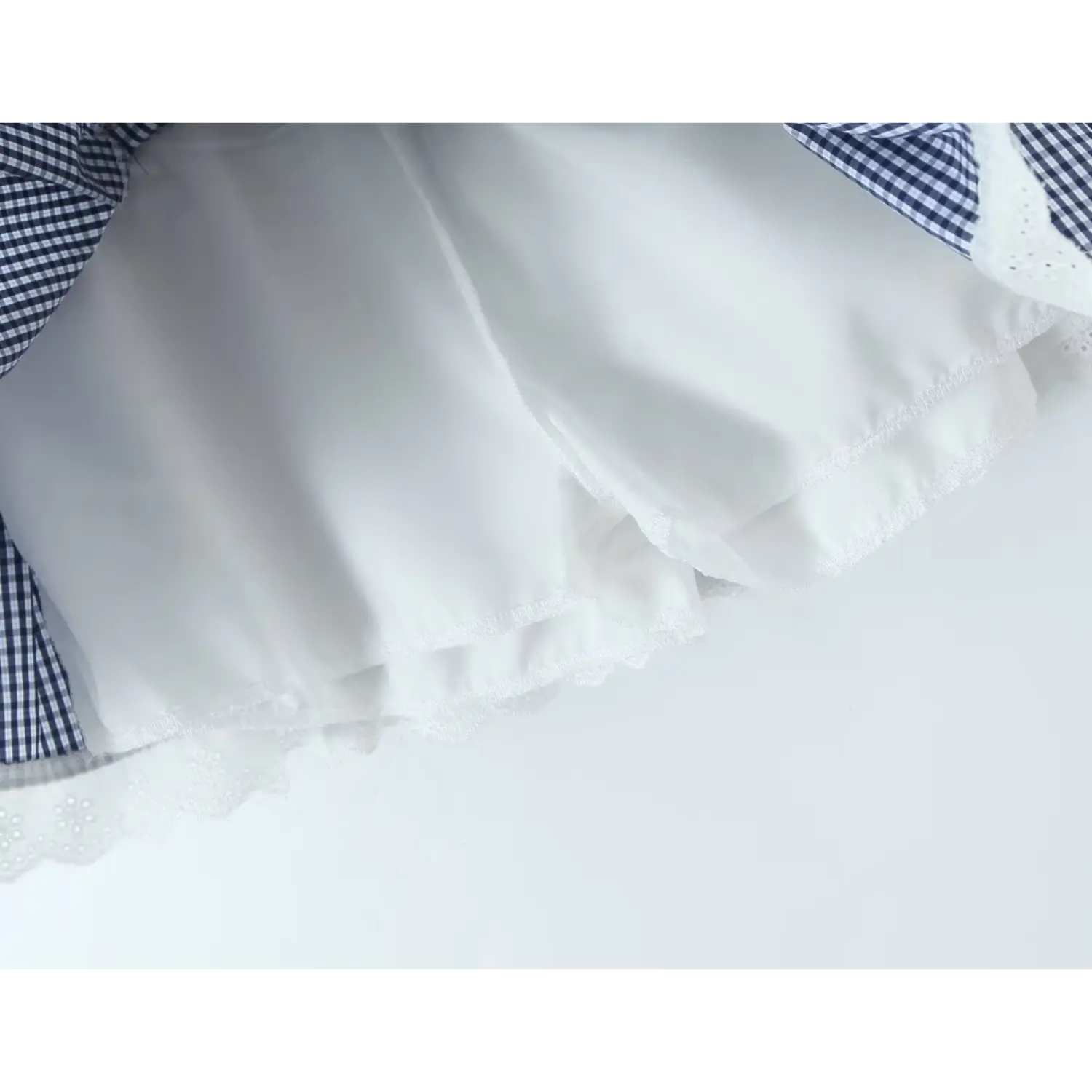 Pleated skirt folded double lining macro close-up, full white skin-friendly inner lining anti-chafing design double serging lace hem lightweight gingham fabric soft drape texture shot