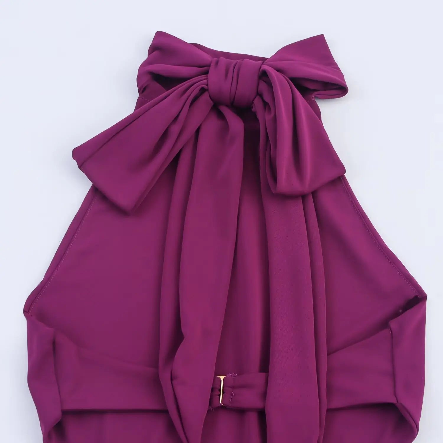 Flat‑lay close‑up of plum dress back halter big bow with metal adjust buckle detail
