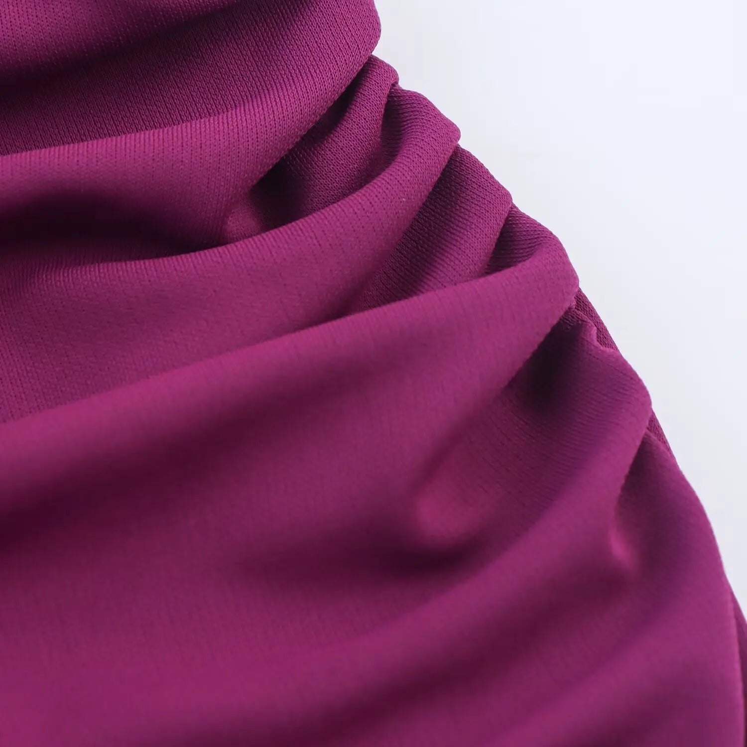 Close‑up showing drape and soft folds of plum stretch knit dress fabric