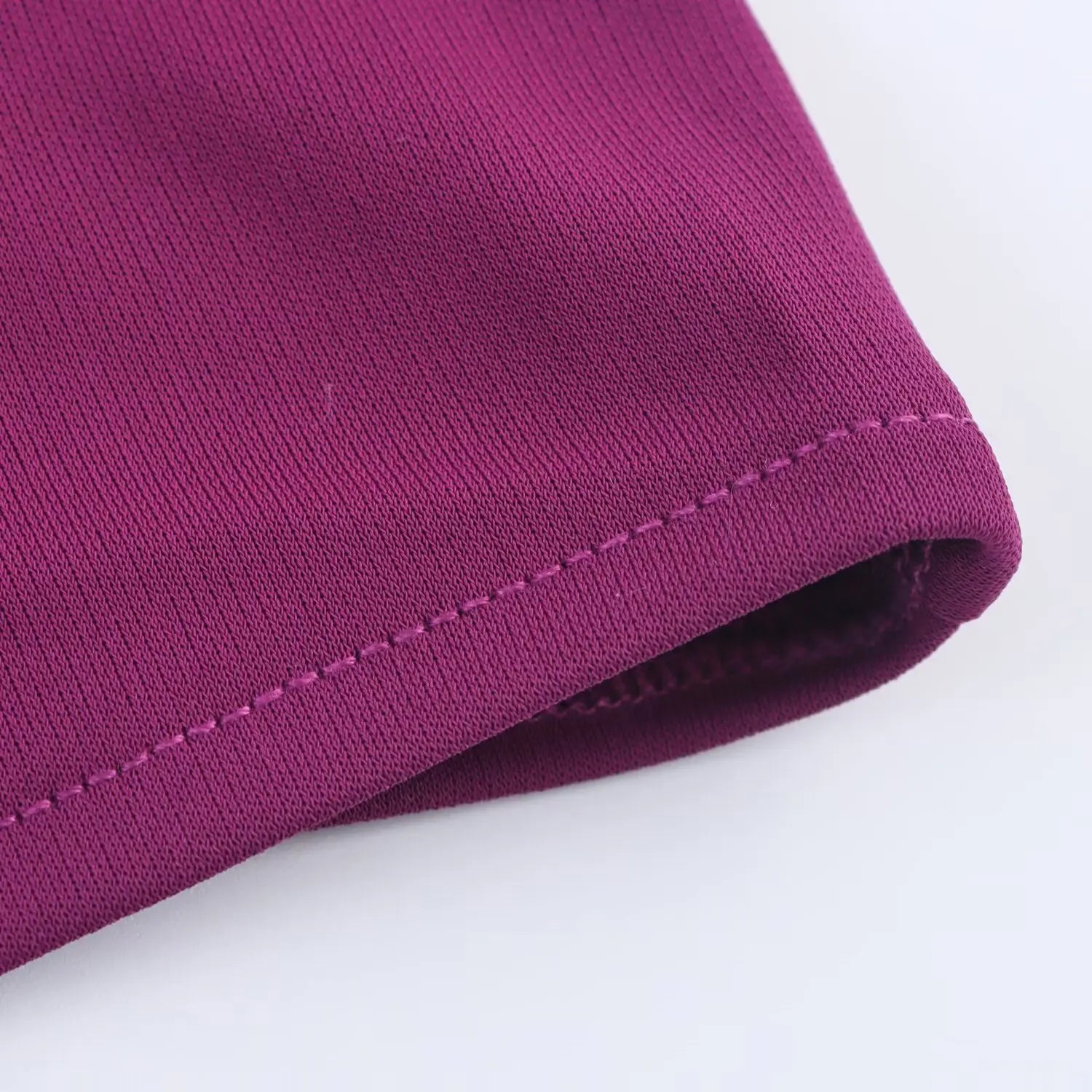 Close‑up of neat finished hem stitching on plum halter bodycon midi dress