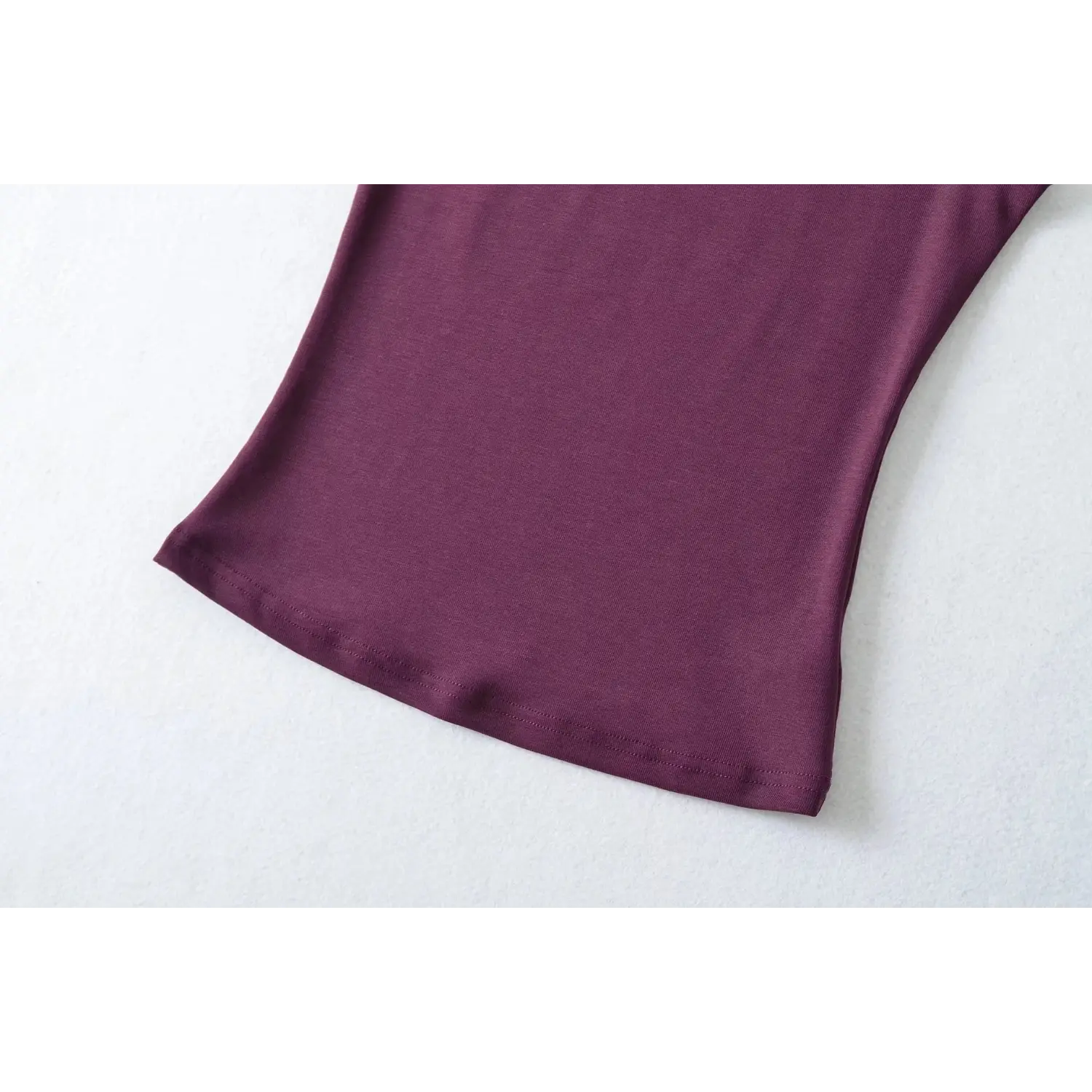 Closeup of bottom hem, plum purple sleeveless turtleneck top, smooth stretch knit material