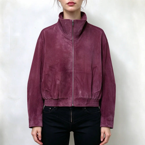 Model wearing plum suede bomber jacket, high stand collar, full front metal zipper, side patch pockets, elastic ribbed hem, long sleeves, relaxed cropped fit, paired with black jeans, plain white background