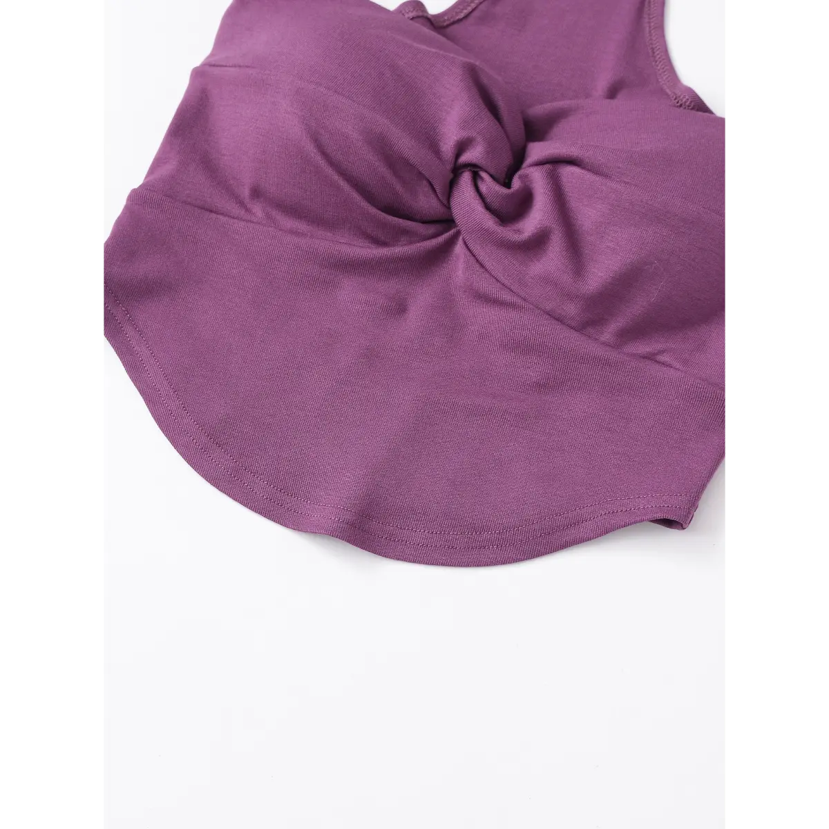 View of the curved finished hem and fitted waist on the plum-colored halter top.