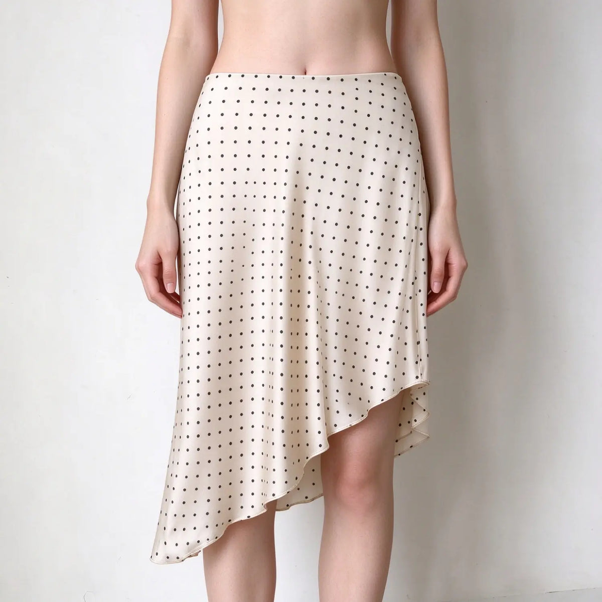 Model wearing polka dot asymmetric handkerchief hem midi skirt, front view