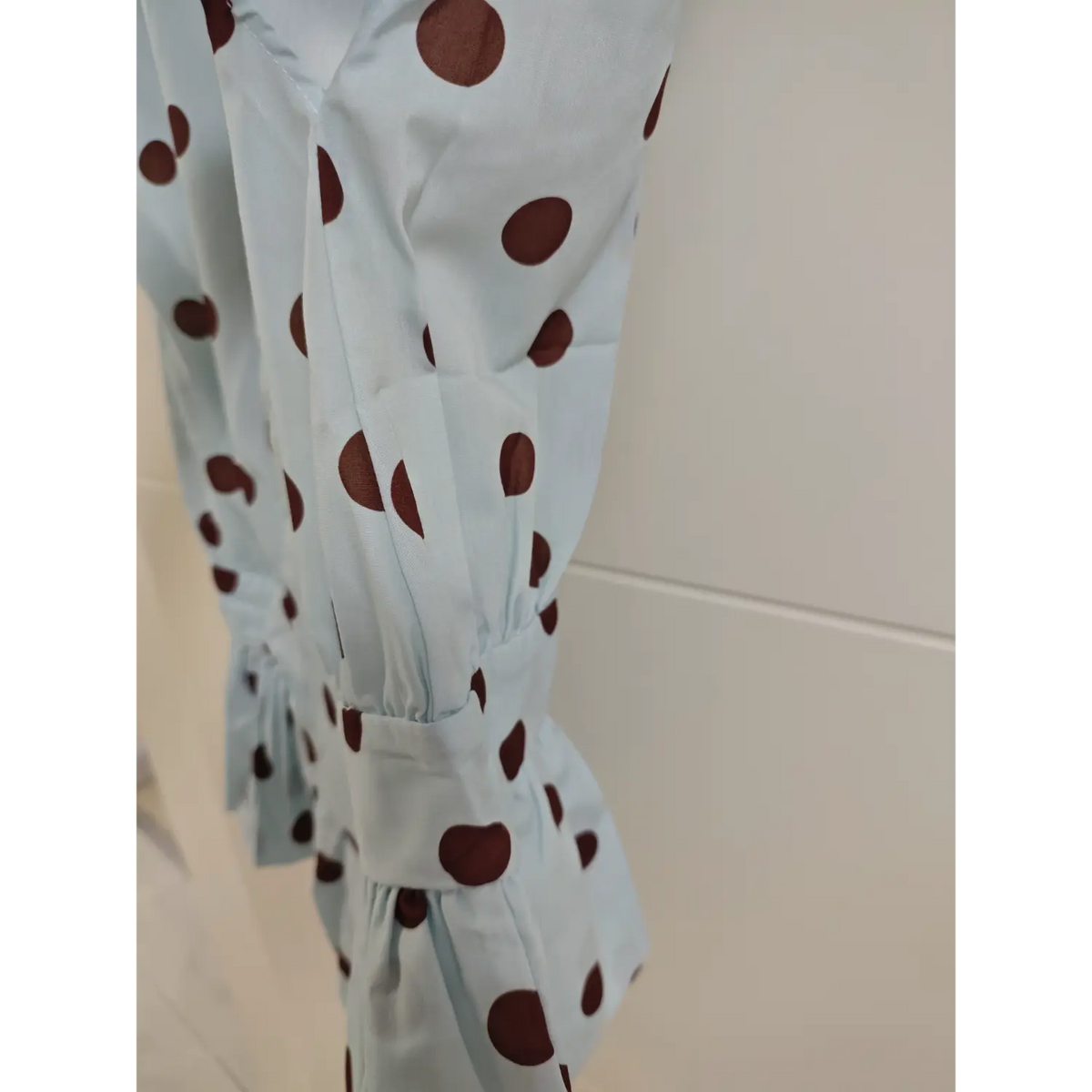 Side partial close-up of polka dot blouse, showing fabric texture, side stitching and peplum ruffle detail