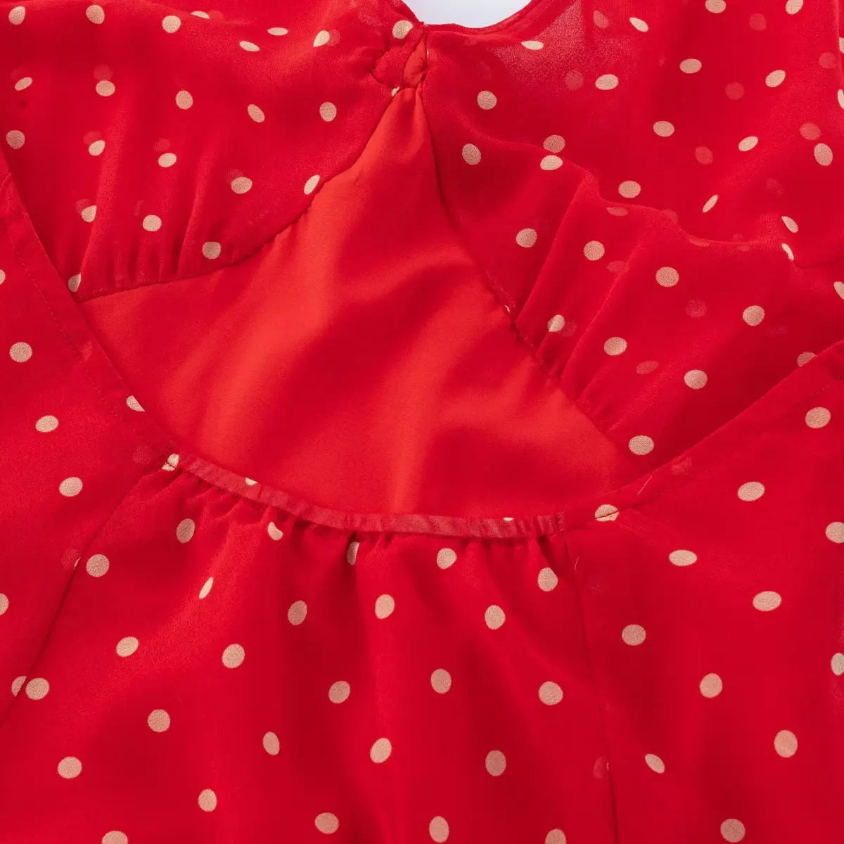 Close-up of gathered bust stitching on red cream dot halter dress, lined inner bust construction.