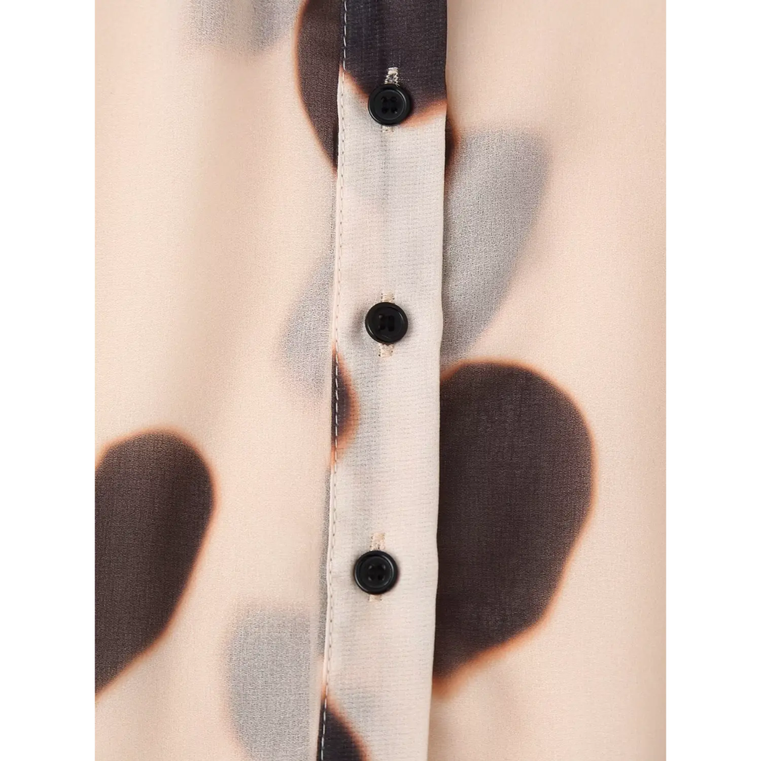 Close up front button placket of sheer watercolor dot shirt, smooth black round buttons and neat stitching