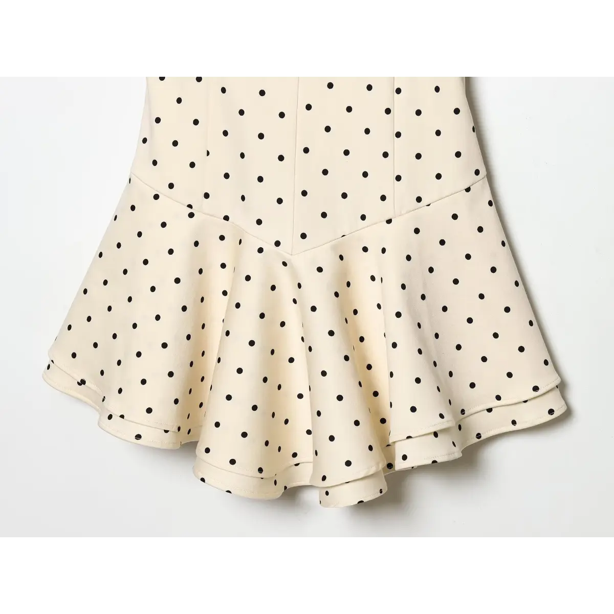 Waist & skirt close of dotted slip dress, structured seamed waist transitioning into cascading double ruffle mini hem.