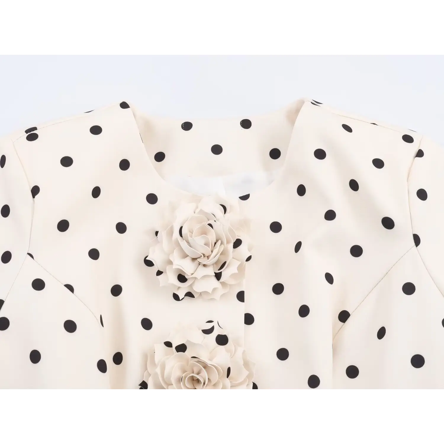 Close-up of round neckline and 3D fabric roses on white polka dot cropped blazer