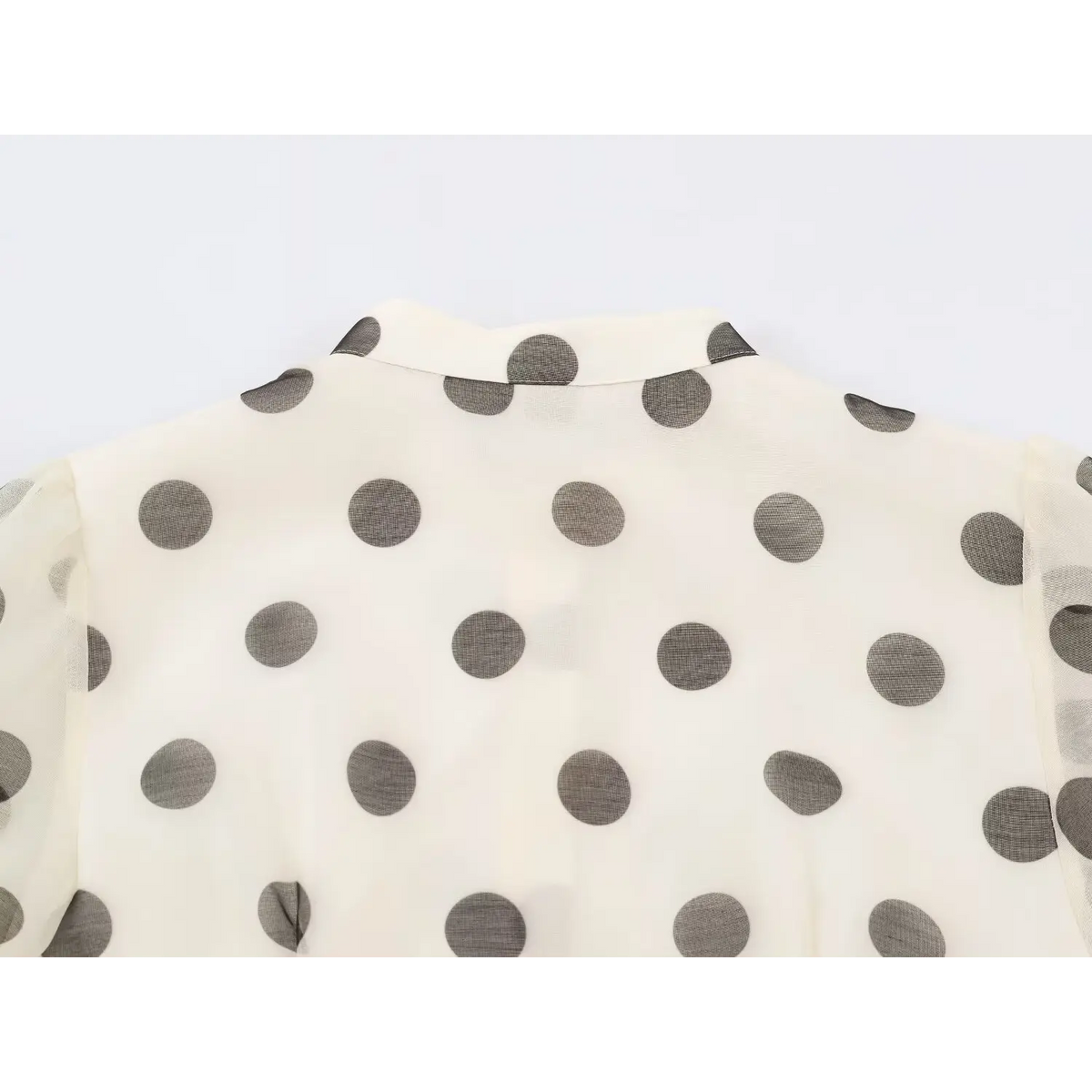 Back view of stand collar and shoulder on semi-sheer polka dot dress
