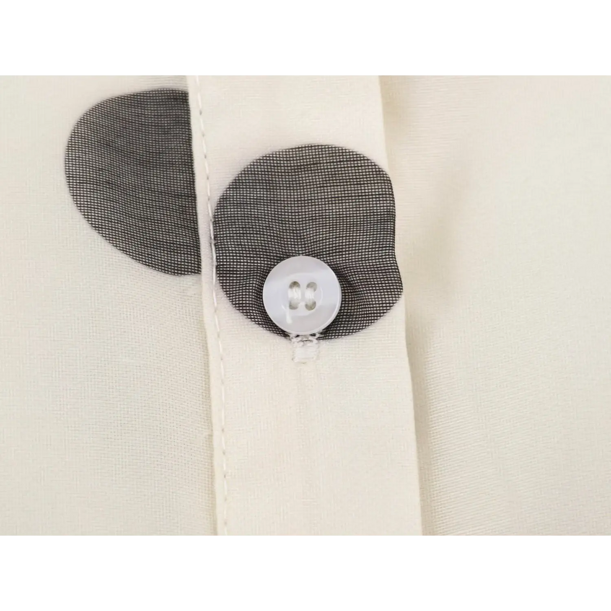 Close-up of white button on black mesh decorative placket of polka dot dress
