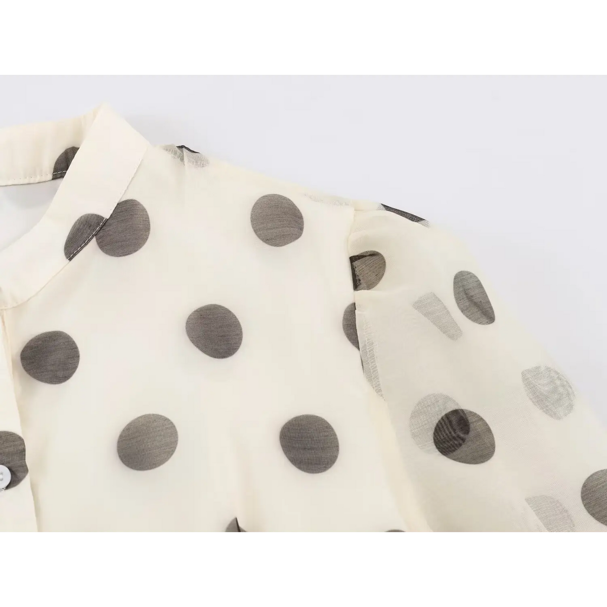 Close-up of stand collar and gathered sleeve on semi-sheer polka dot fabric