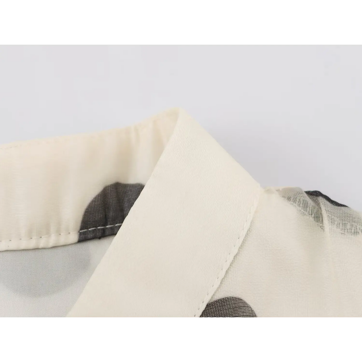 Close-up of neat collar stitching on polka dot fabric with black mesh trim