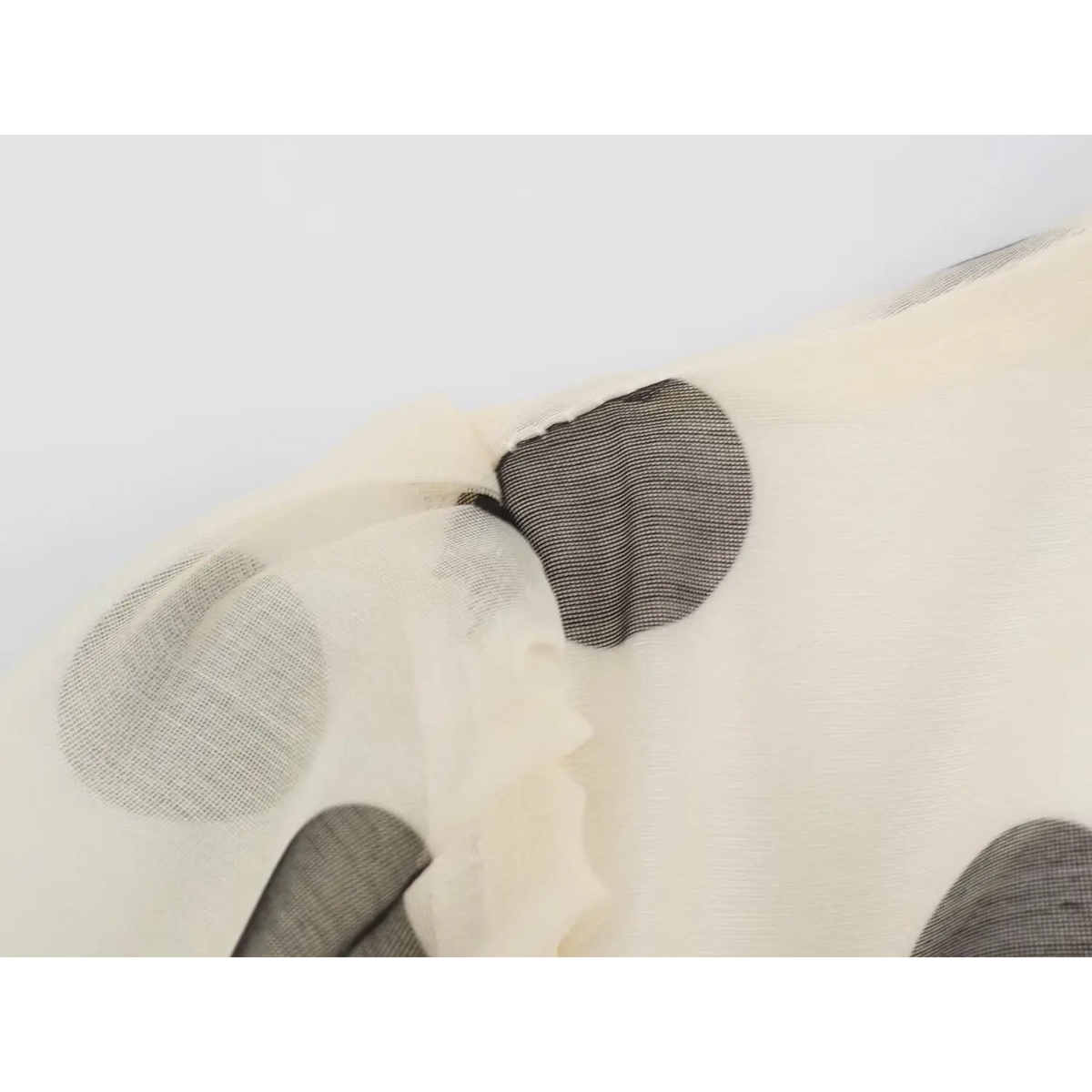 Close-up of cream mesh fabric with charcoal polka dot print