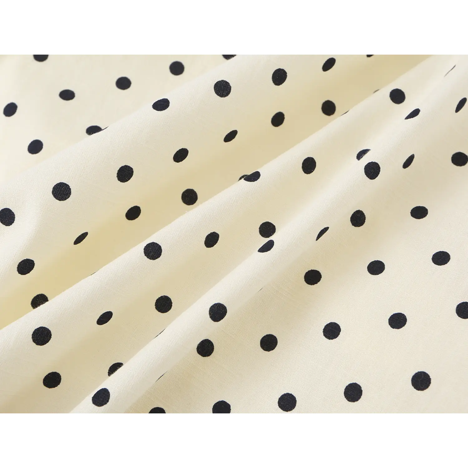 Draped fabric fold detail shot, matte soft woven texture, regular spaced black polka dots