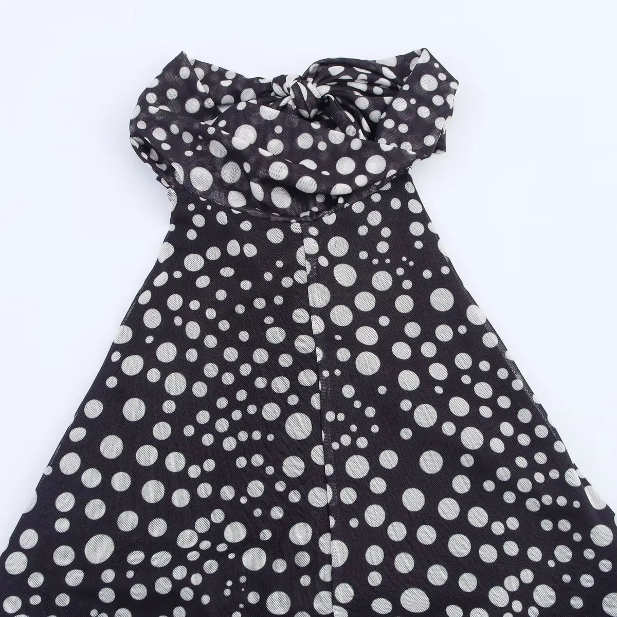 Flat lay of polka dot halter maxi dress with twisted halter neck straps on white background