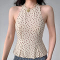 Model wearing a beige halter peplum top with red polka dots, showcasing the high neck, fitted bodice, and flared peplum silhouette.