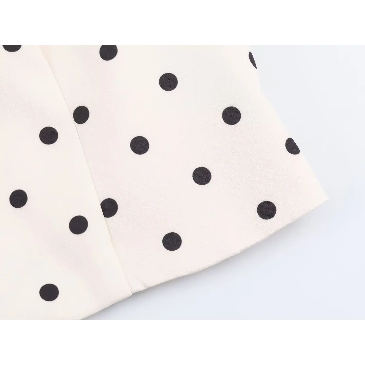 Close-up side seam stitching detail on white black polka dot cropped blazer hem