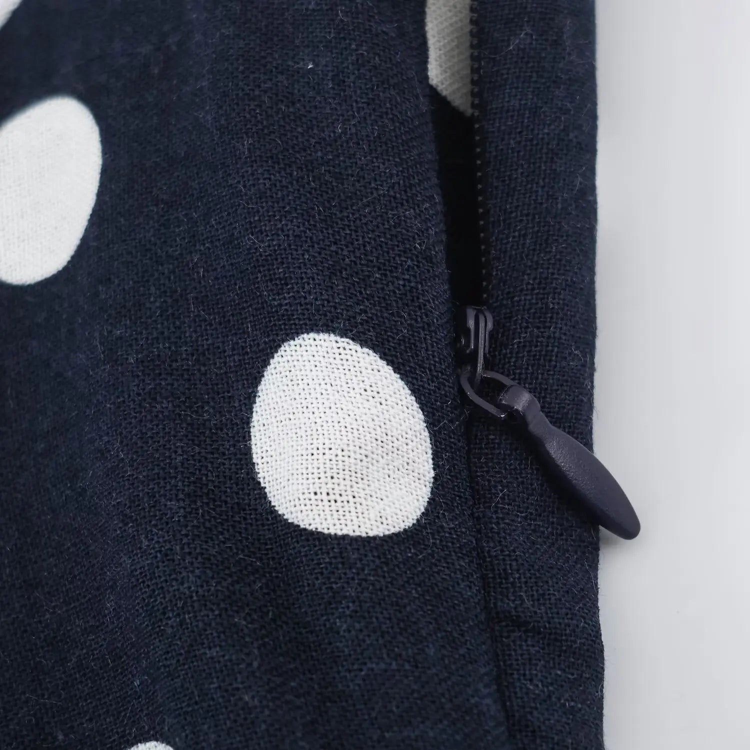 Close‑up of invisible side zipper, navy polka dot woven fabric, concealed zipper closure