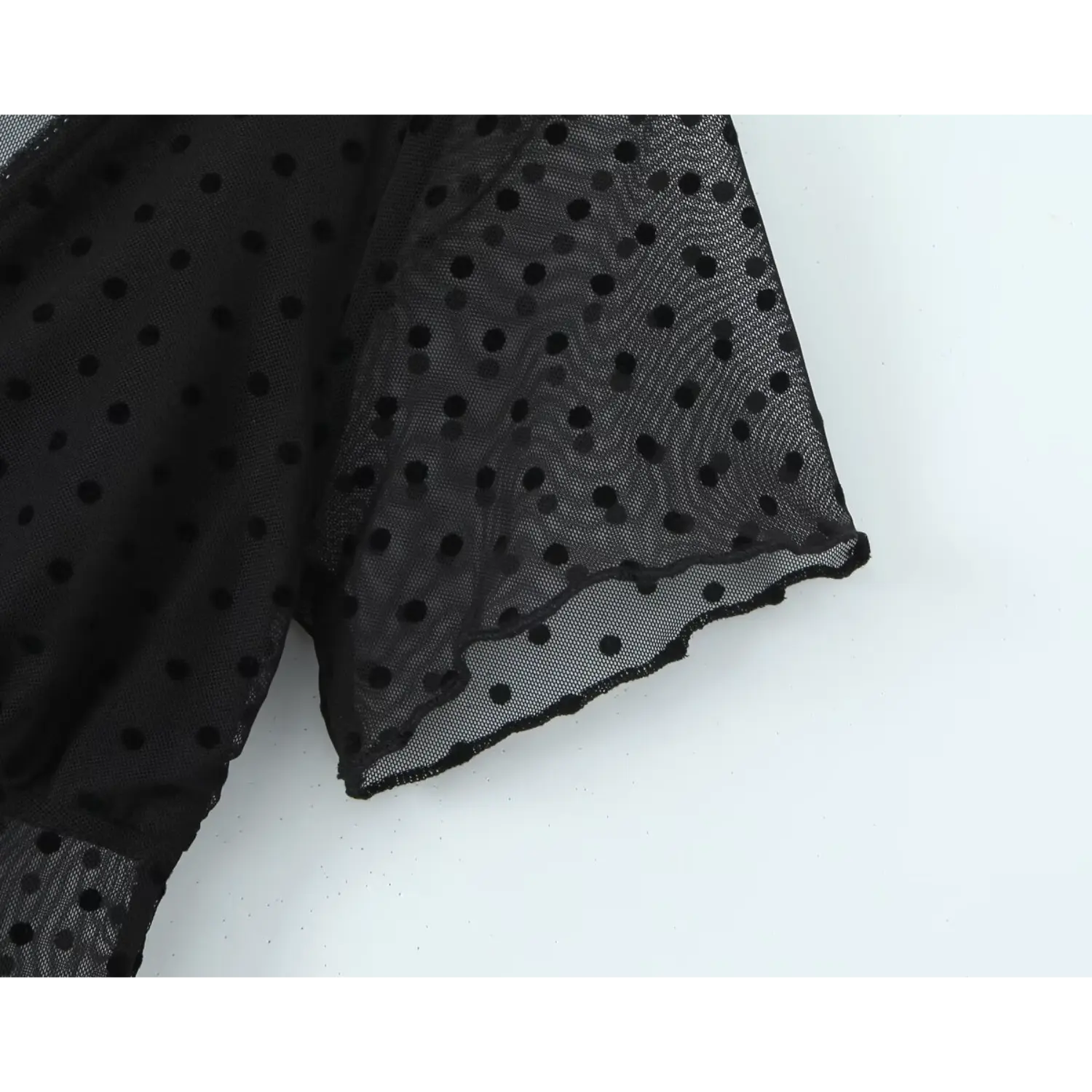Close‑up short sleeve scalloped cuff of black polka dot sheer mesh dress