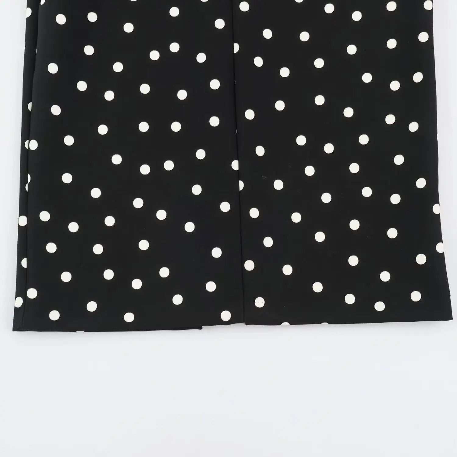 Flat view of dress hem with back centre slit, black fabric white polka dots
