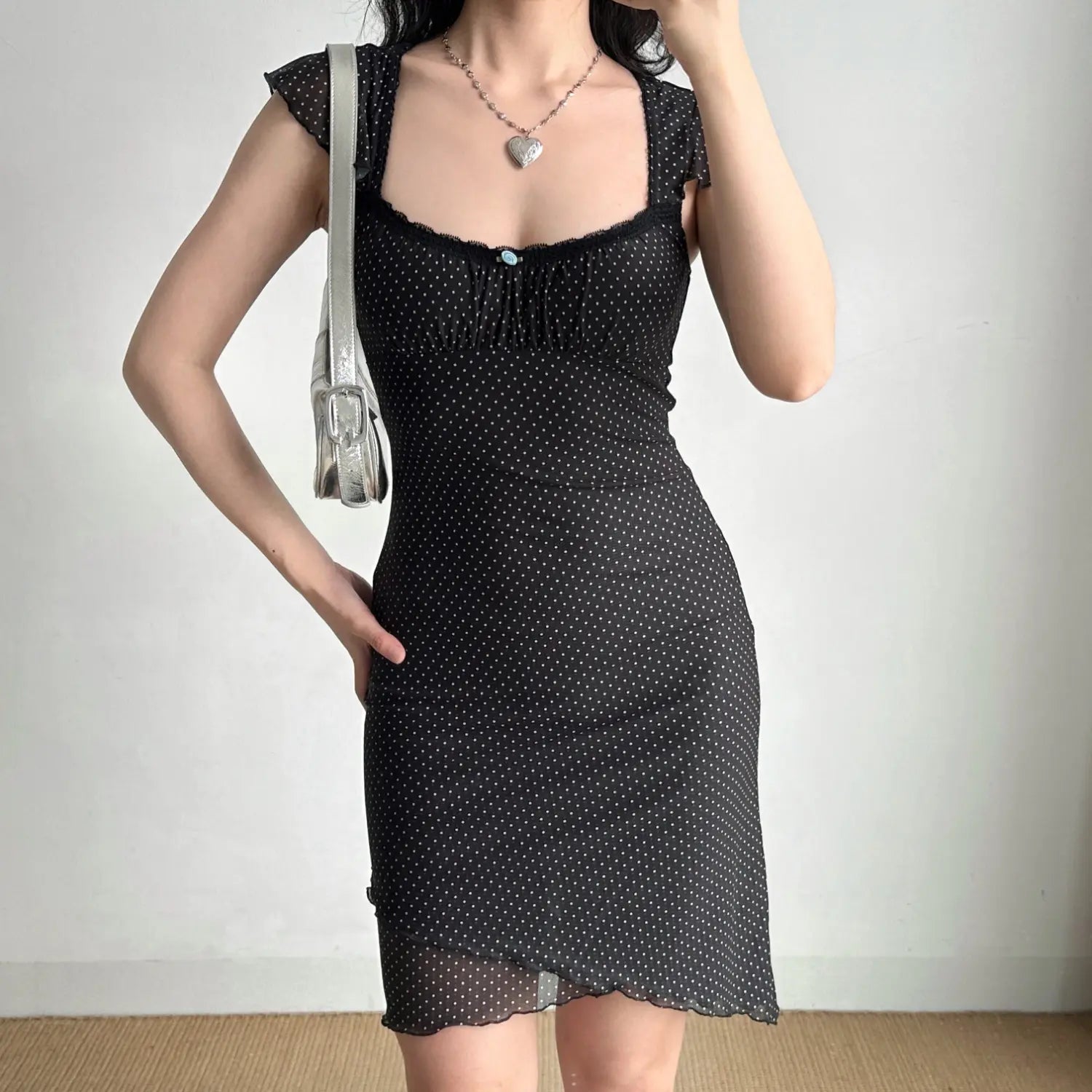 Studio front shot black white polka dot mesh mini dress, square neck lace trim, ruffle cap sleeves, fitted ruched skirt asymmetrical lettuce hem