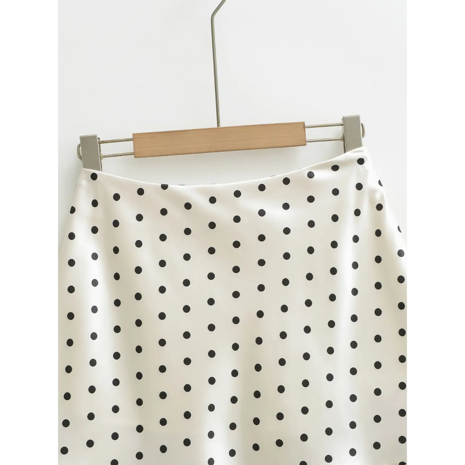 Full waist hanging view, white polka dot high waist satin A-line mini skirt on wooden metal hanger