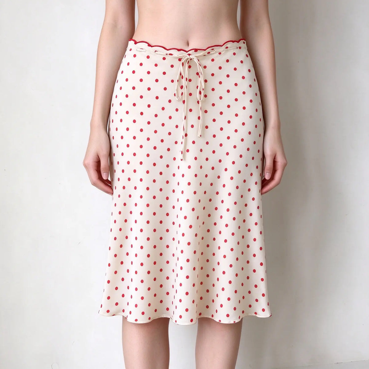 Model wearing polka dot scalloped waist satin slip midi skirt, front view