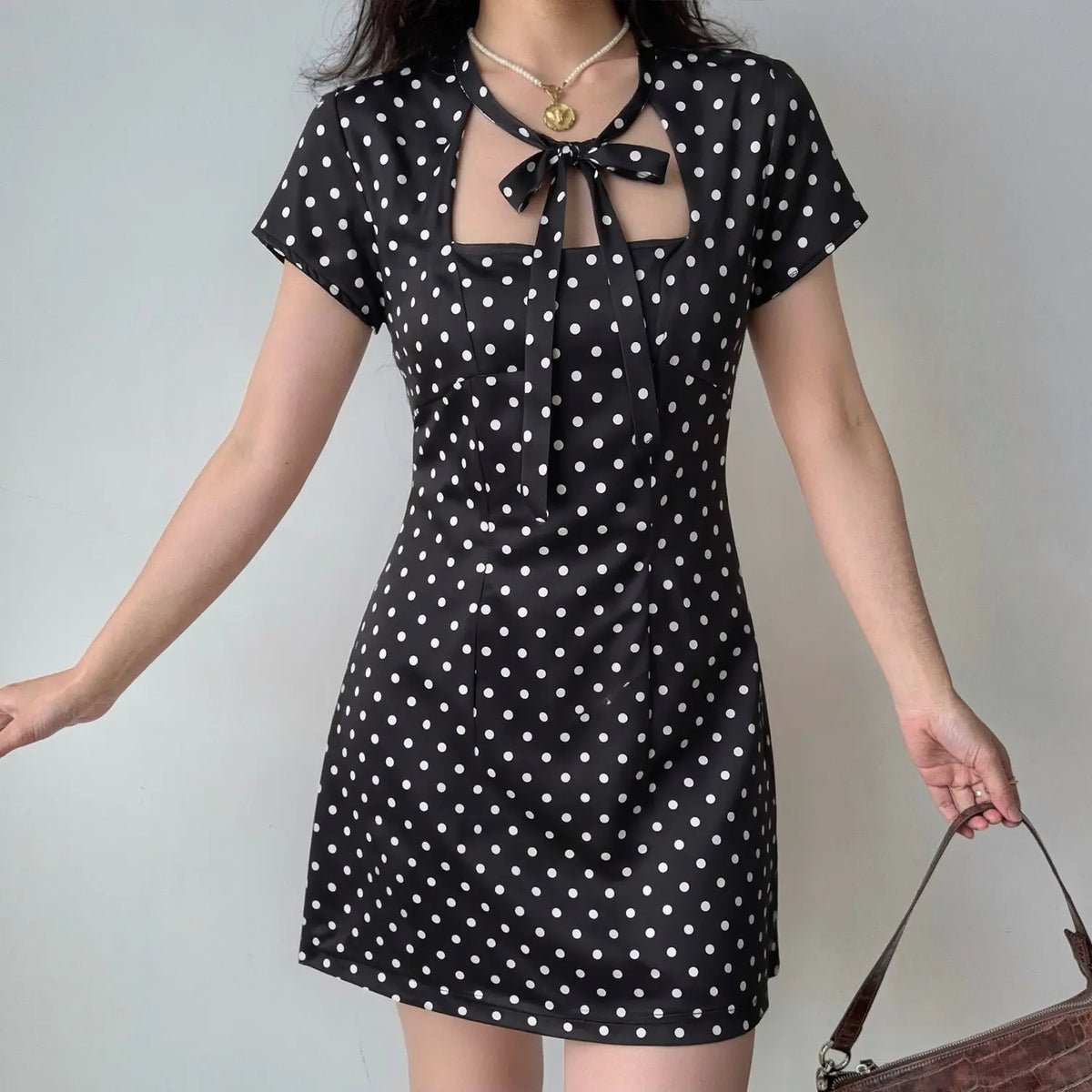 Model wearing black polka dot tie neck short sleeve mini dress