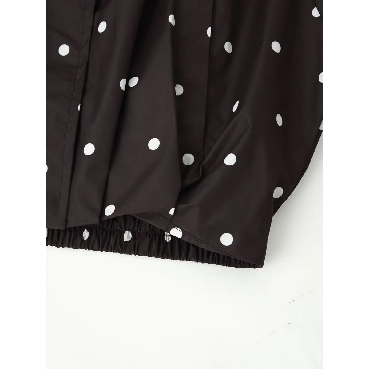 Bottom hem close‑up, elastic gathered hem of black polka dot cropped windbreaker