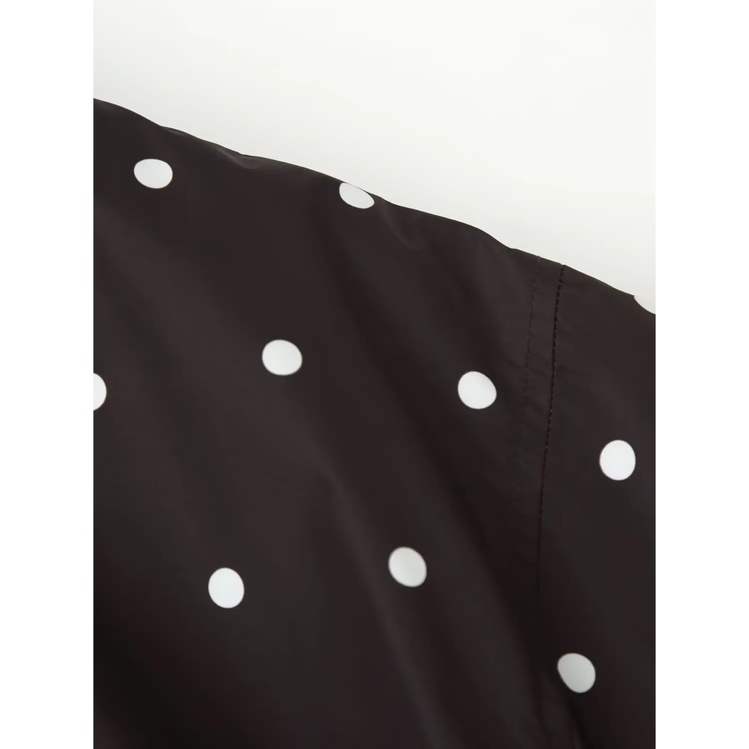 Fabric and shoulder seam close‑up, black shell fabric with white polka dot print