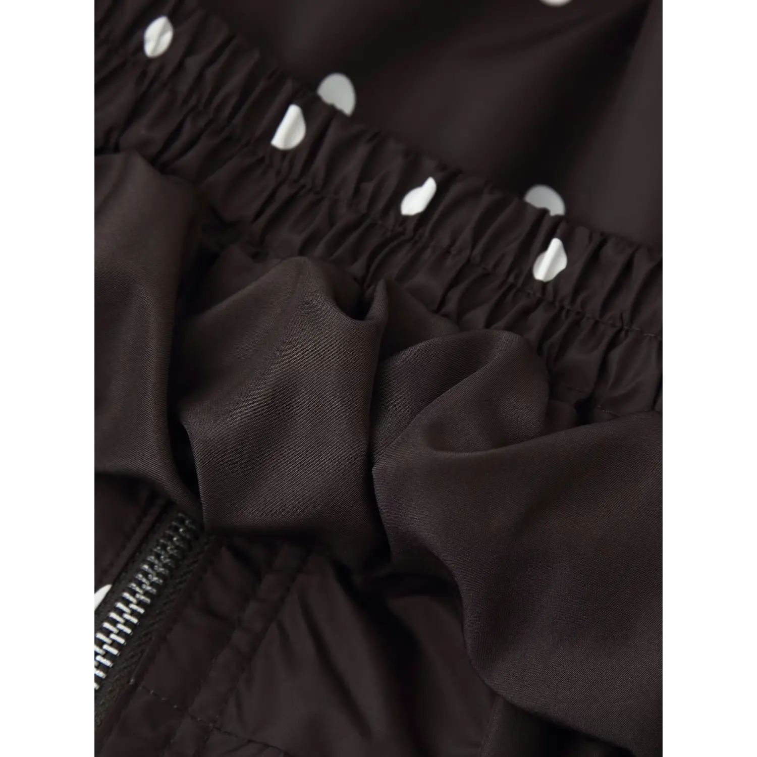 Inner view of elastic hem, shell fabric texture close‑up of polka dot windbreaker