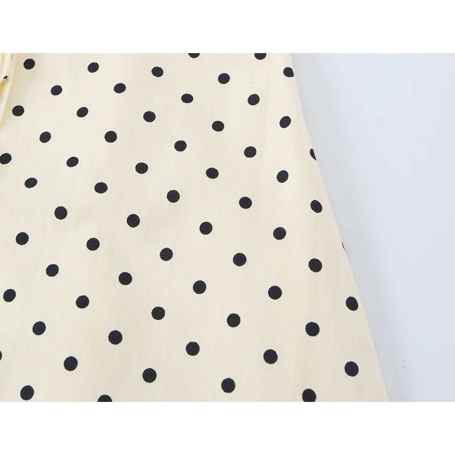 Fabric flat texture close-up, uniform black dot print on cream lightweight woven material