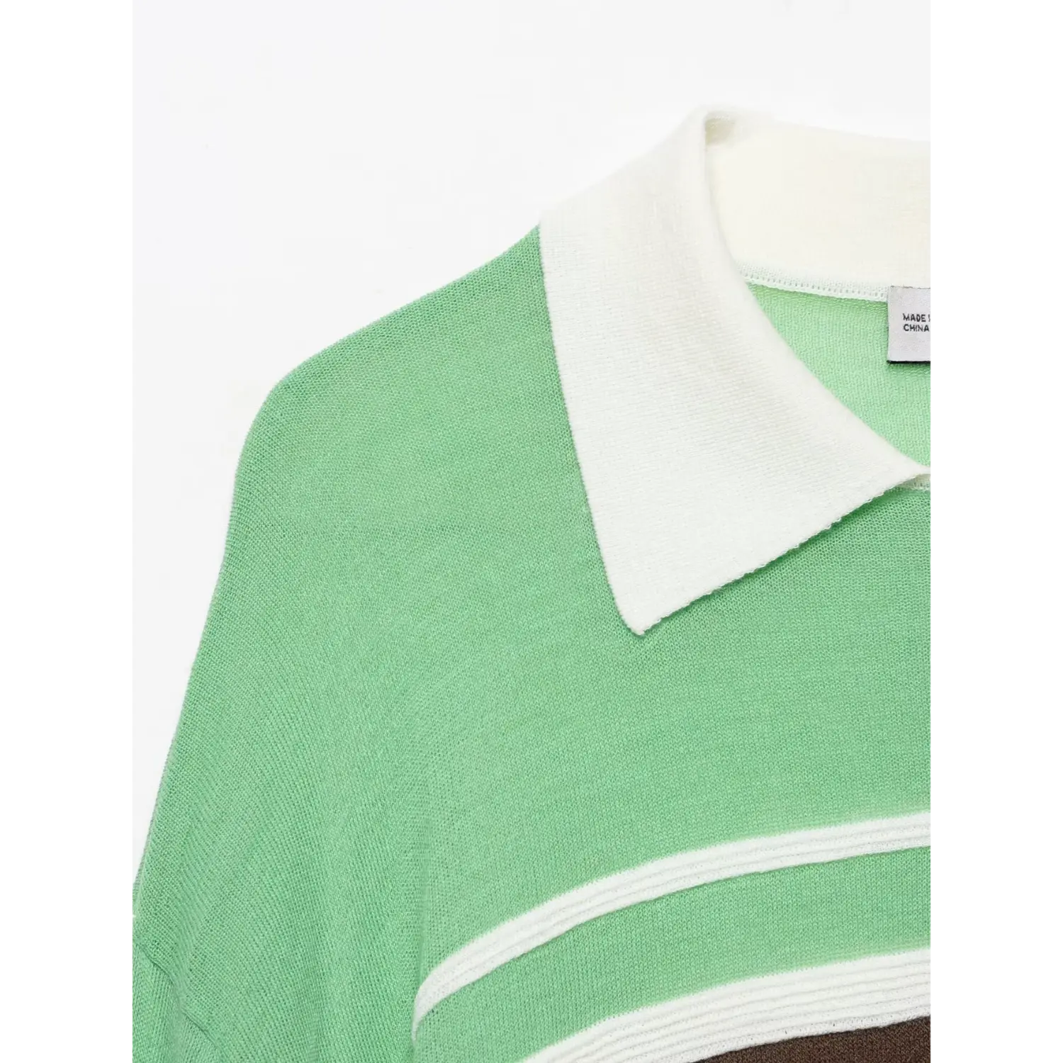 Close‑up of white polo collar and shoulder, fine lightweight green knit fabric texture