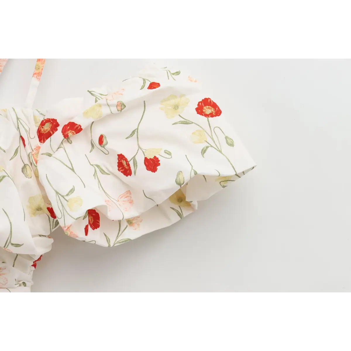 Close-up of the puff off-shoulder sleeve on a white poppy-print dress, highlighting the gathered construction.