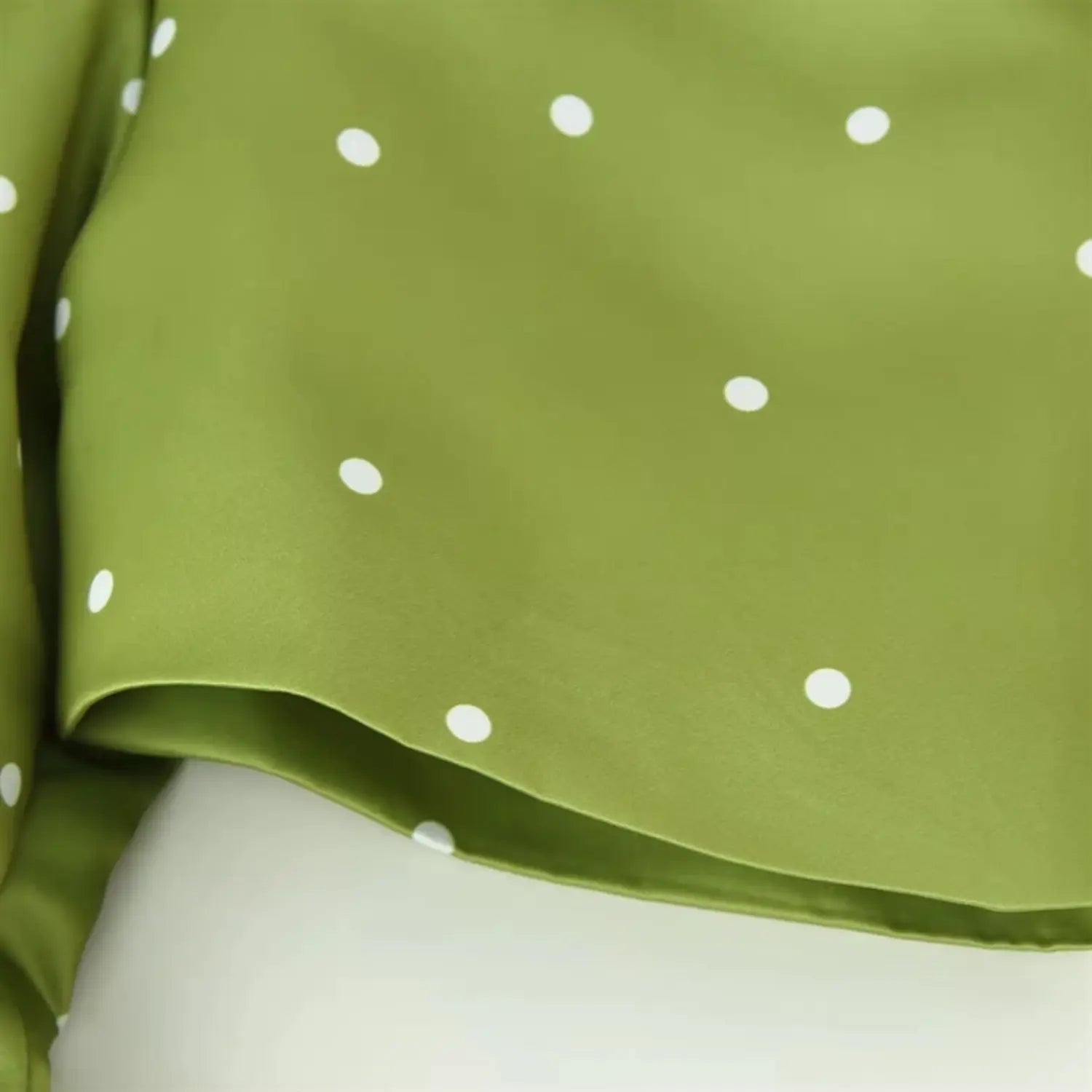 Short sleeve cuff hem close-up, narrow folded binding, neat uniform serging stitch, soft satin drape