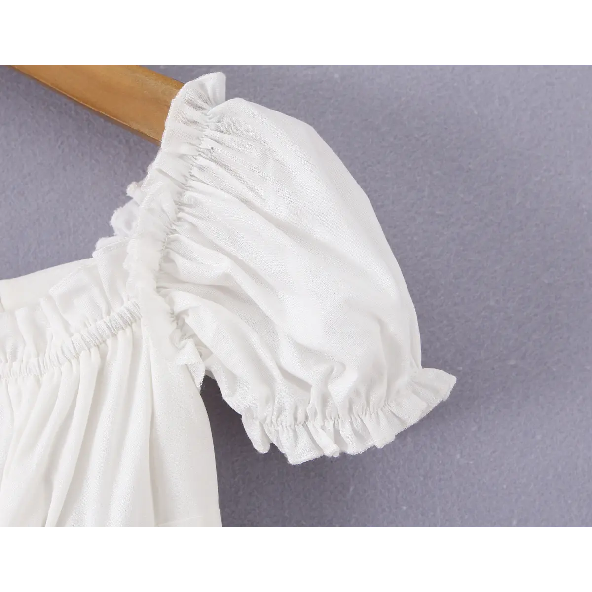 Close-up of the puff sleeve on a white off-shoulder peplum top, showing the ruffled elasticated edge and gathered construction.