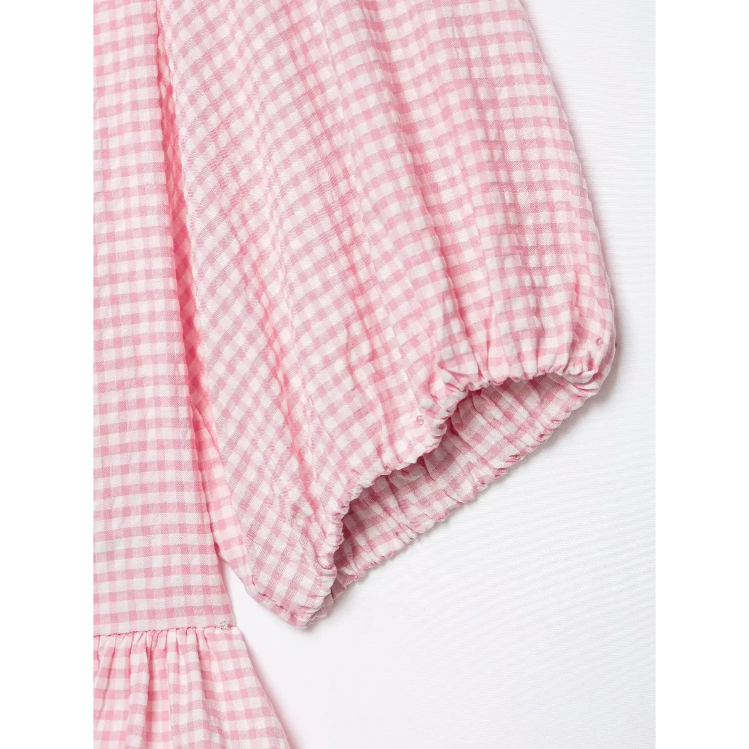 Sleeve close-up, gathered elastic cuff, small inner securing button, crinkle pink gingham fabric structure