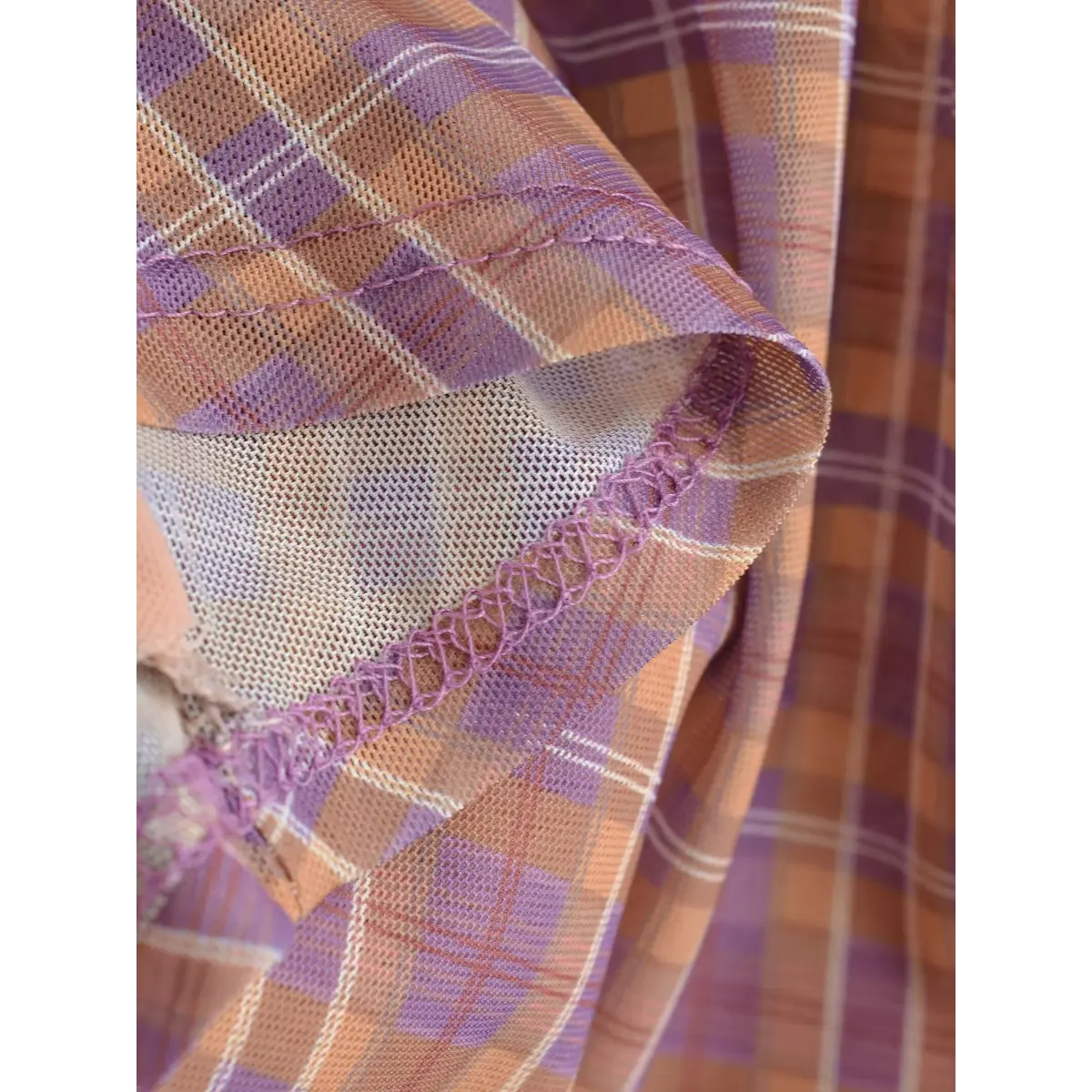 Close-up of the mesh fabric edge, featuring clean overlock stitching in matching purple thread.