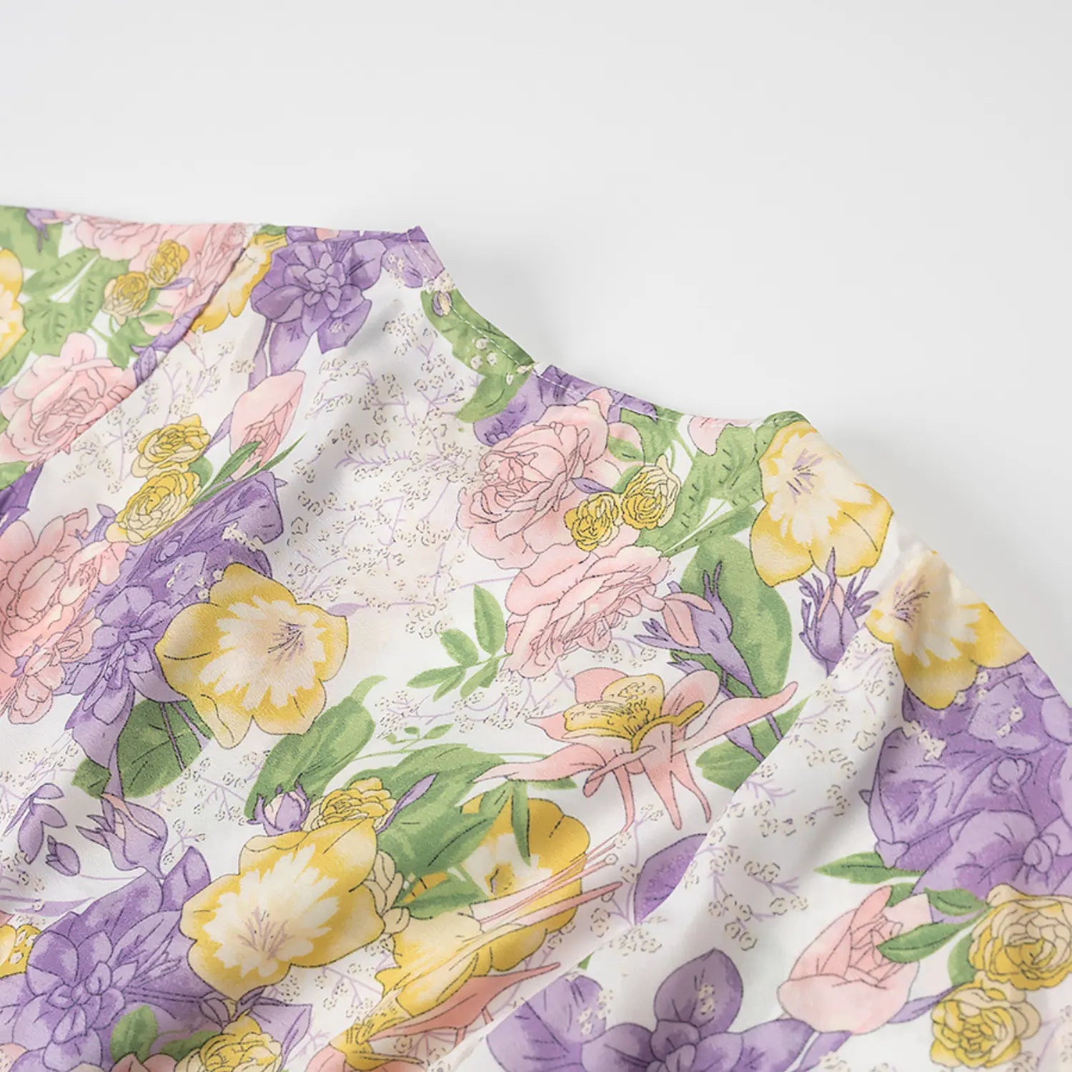 Close-up view of v-neck ruffle collar on white base floral mini dress with purple pink yellow vintage flower print